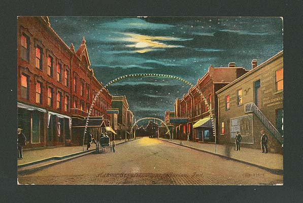 (ca. 1900) So. Adams St., night view, shows Spencer Hotel on left, decorative lights in arch over street.